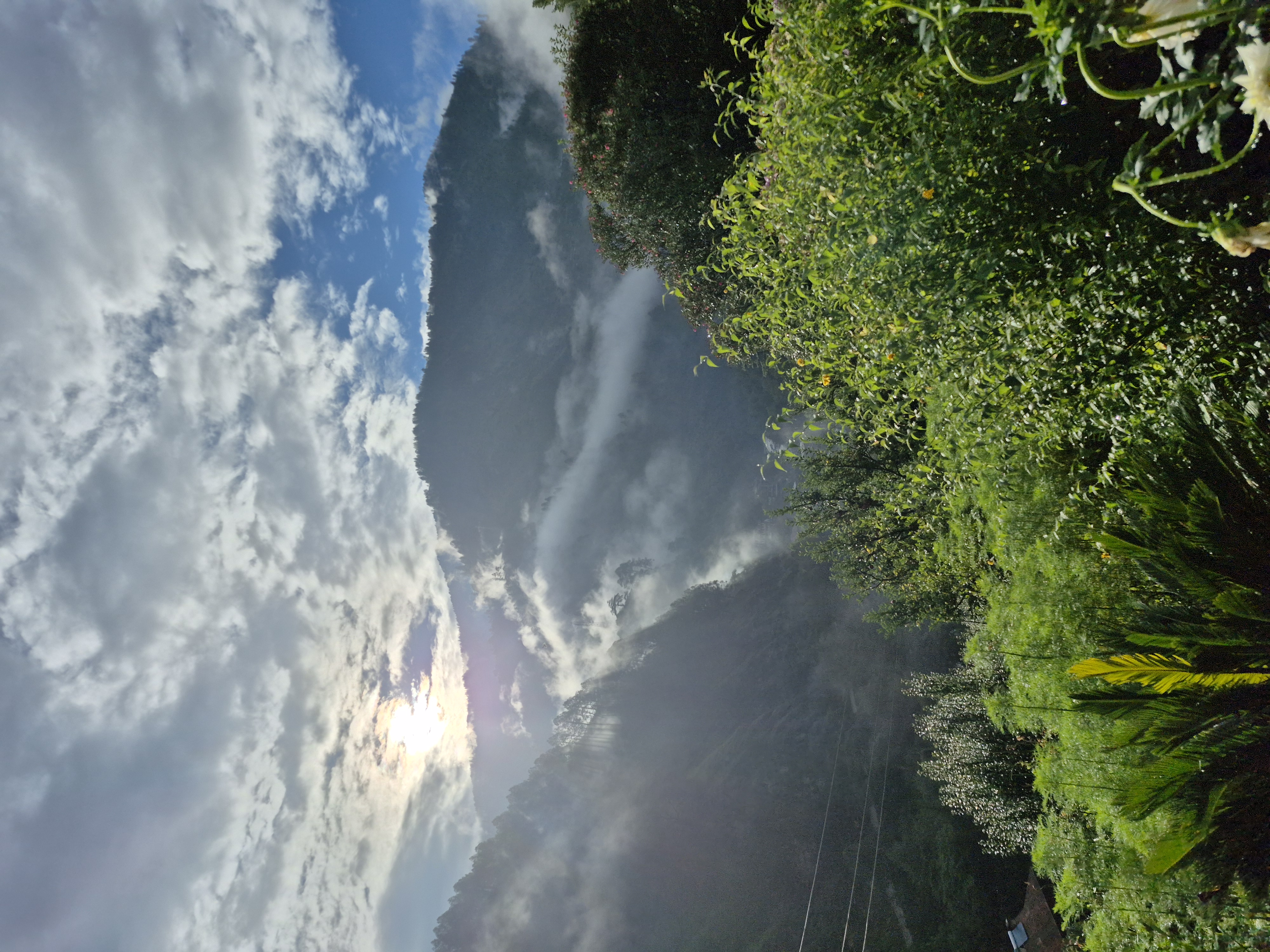 Sunlight breaking through clouds above misty forested mountains